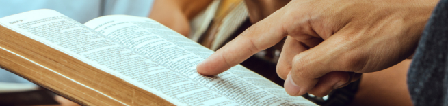 Open bible with someone pointing to a verse