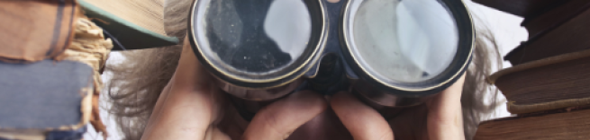 A lady with binoculars stares between piles of books