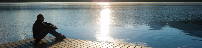 someone sitting on a pier looking at a lake