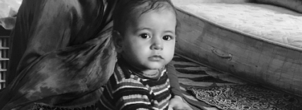 A mono image of an infant held by their mother