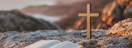 A small cross and an open bible on a hill top