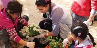 Children planting flowers in pots.