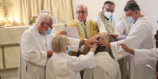 Clergy members placing their hands on anothers head.