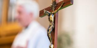 man blurred in the background with a cross in the forground 