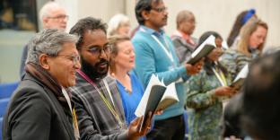 People singing at a conference holding books