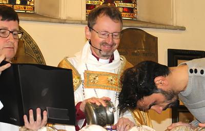 Bishop Robert performing a baptism whilst beaming with joy.