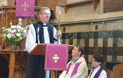 Bishop Robert speaking at the front of a church.