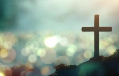 A cross silhouetted against a bokeh sky