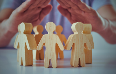 Wooden cut out people protected by hands