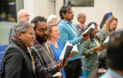 People singing at a conference holding books