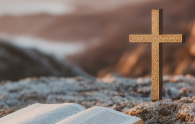 A small cross and an open bible on a hill top