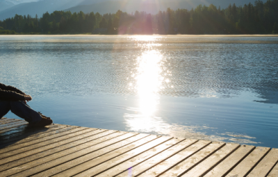 someone sitting on a pier looking at a lake