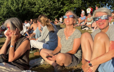 people in a park with eclipse glasses on