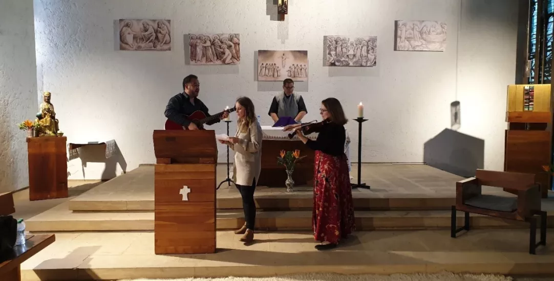 People singing and playing guitar at the front of a church.