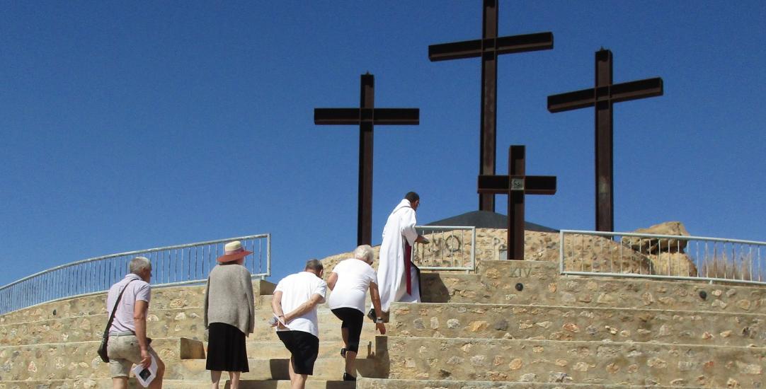 people walking up steps with a cross at the top