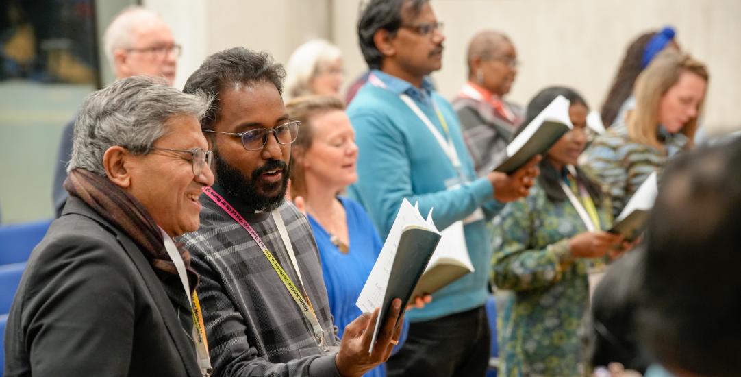 People singing at a conference holding books