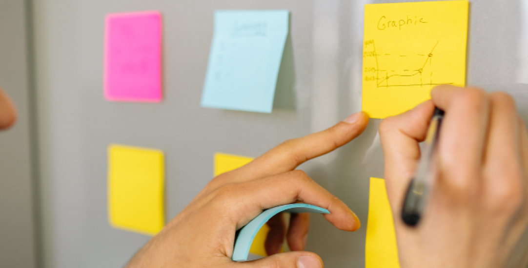 man writes on post in notes